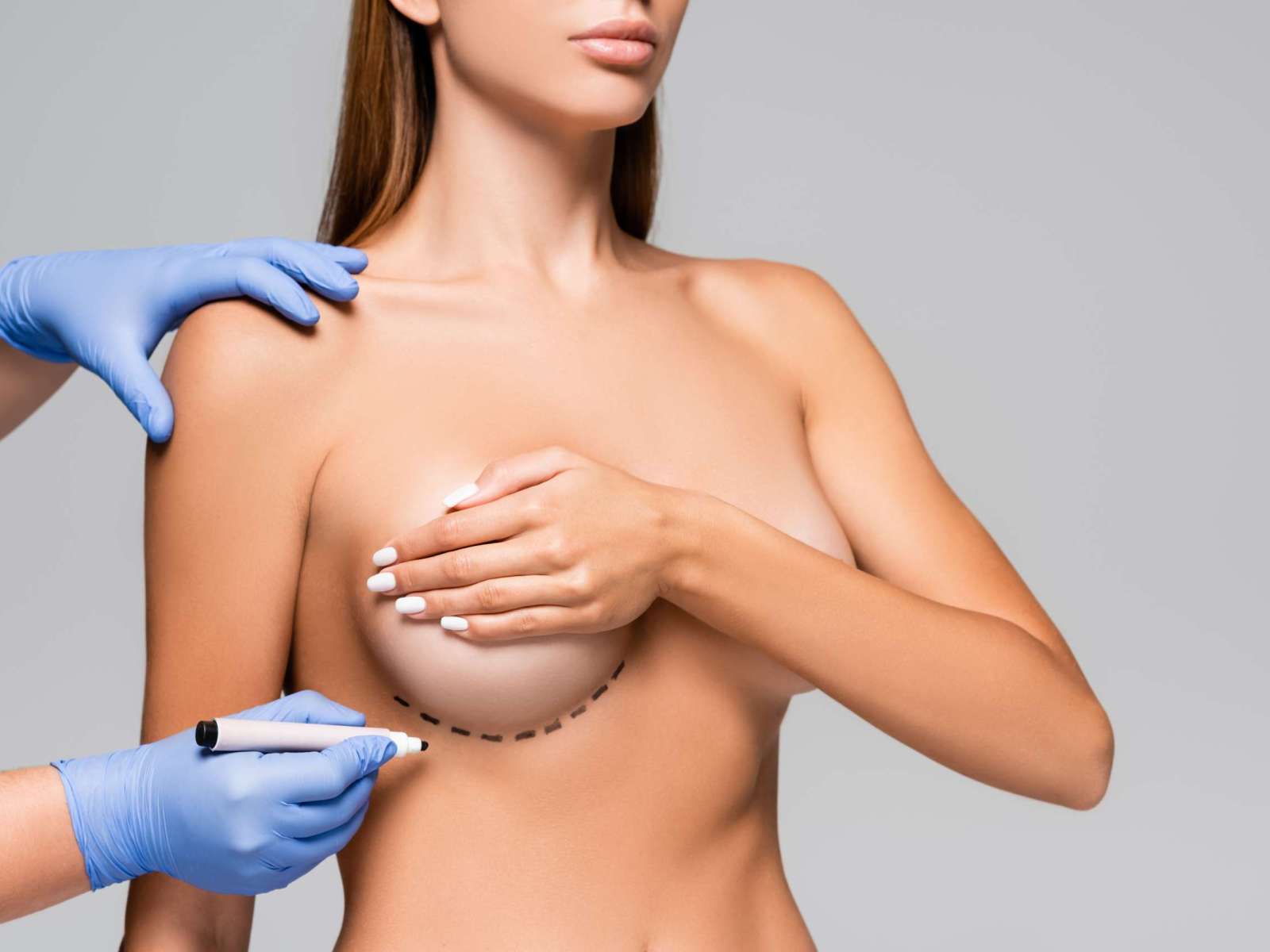 Cropped view of doctor holding marker near bust of naked woman with marks isolated on grey